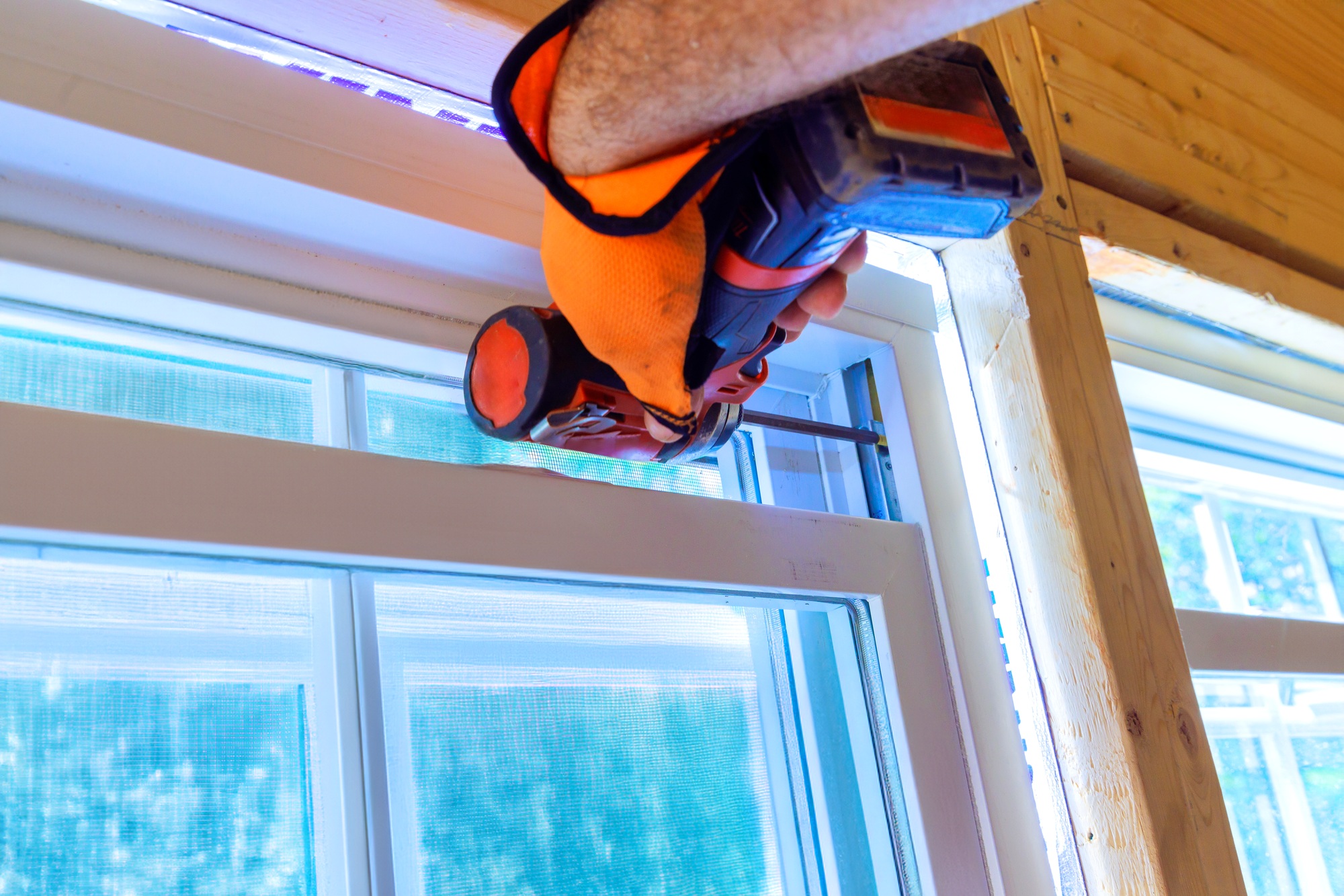 Construction worker installs window in new house is uses a screwdriver