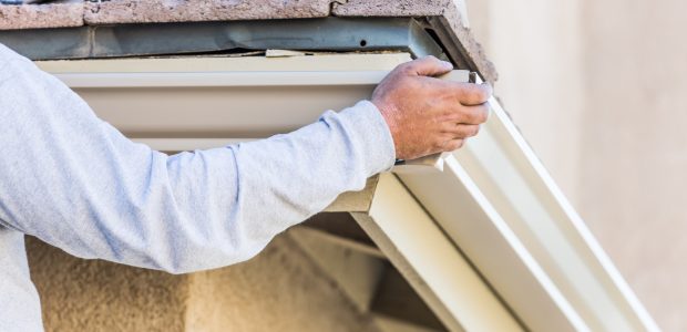 Worker Attaching Aluminum Rain Gutter to Fascia of House